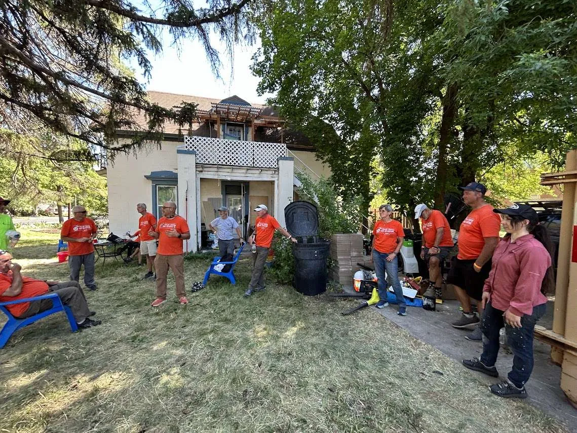 Volunteers gathered in a yard beside a house