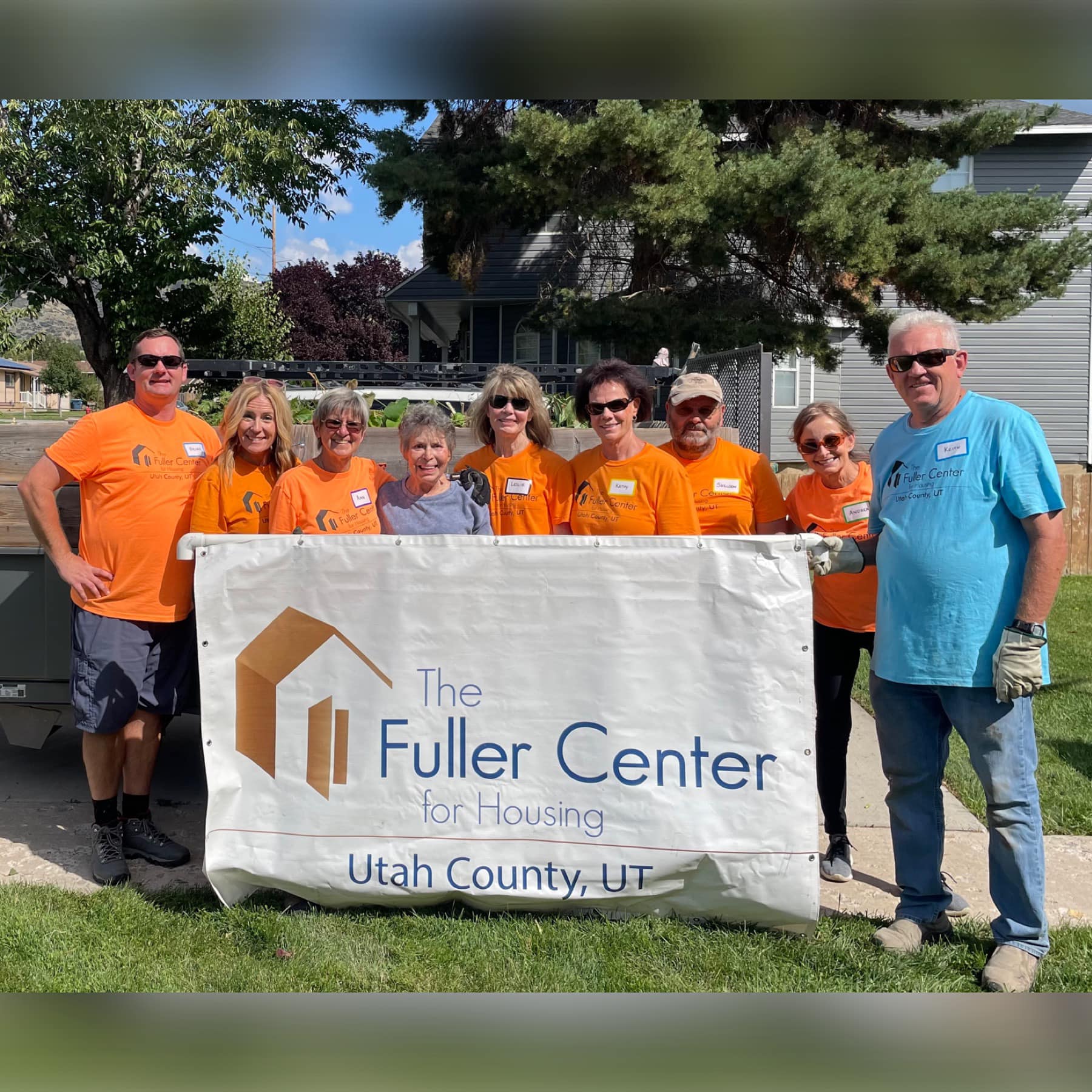 Volunteers standing behind a Fuller Center for Housing Utah County banner